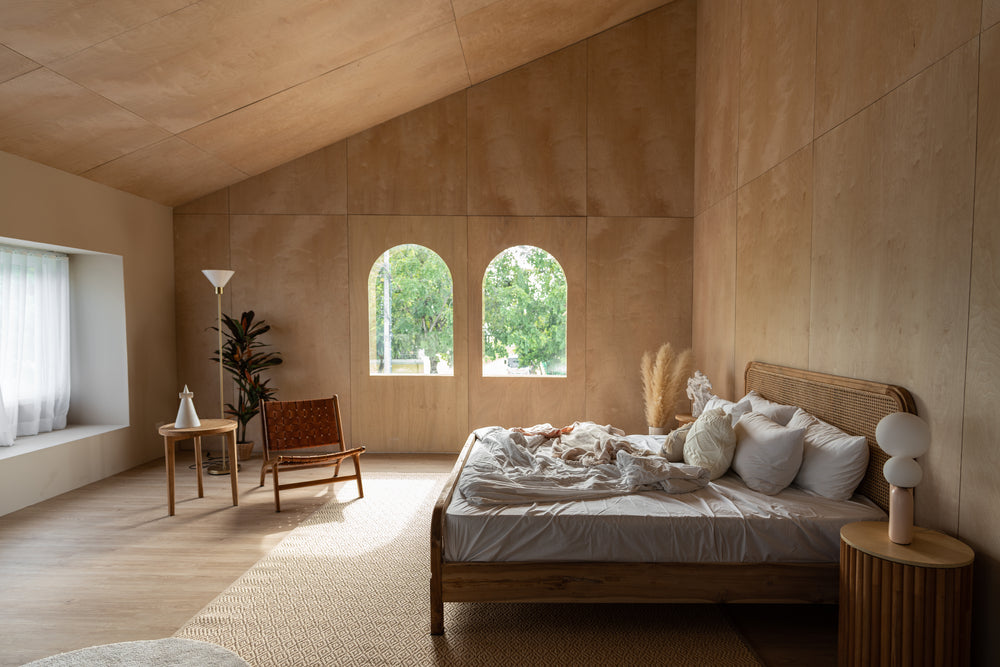 Stylish Bedroom corner with rattan headboard and bed with soft pillows setting with white pillows plywood wall on the background